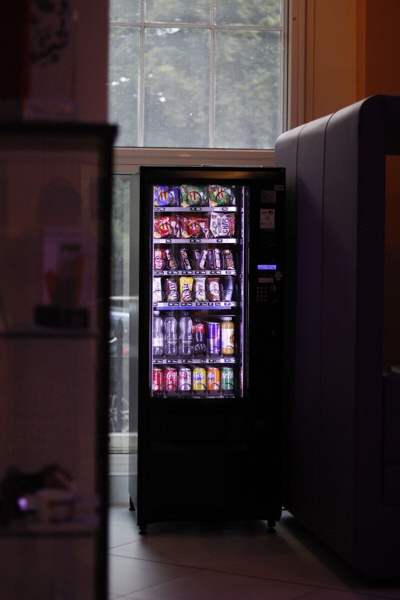 A vending machine sitting next to a window